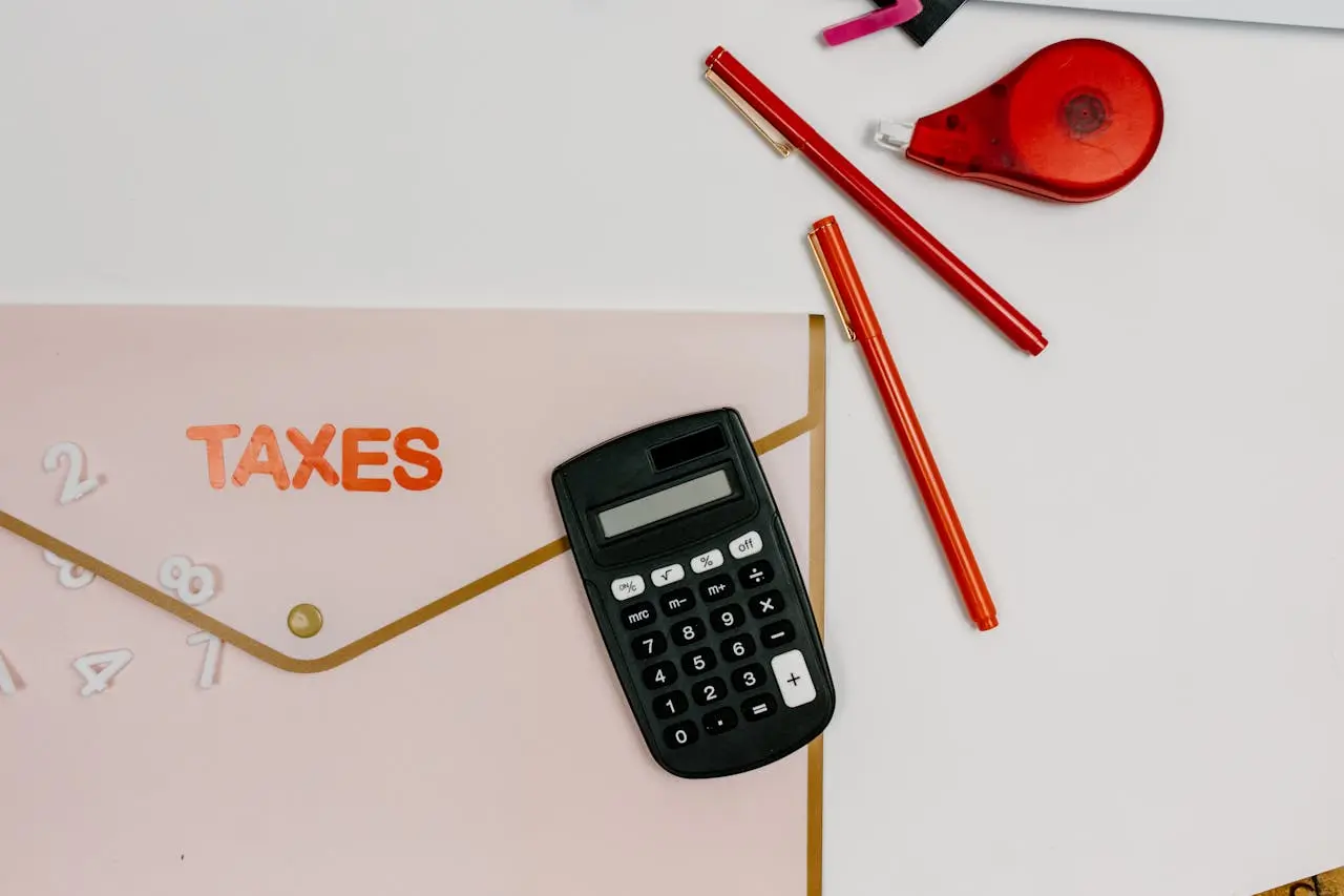 about-us Flat lay image featuring a calculator, pens, and a folder labeled 'TAXES', perfect for finance-related themes.